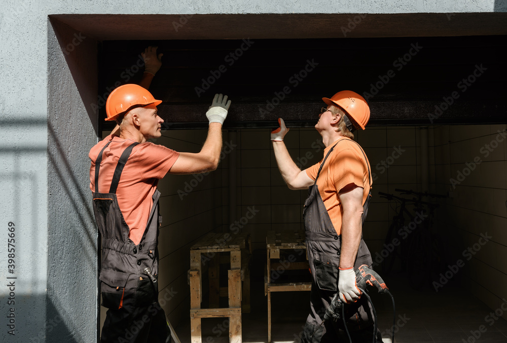 professionals in orange work hats and shirts working on garage door