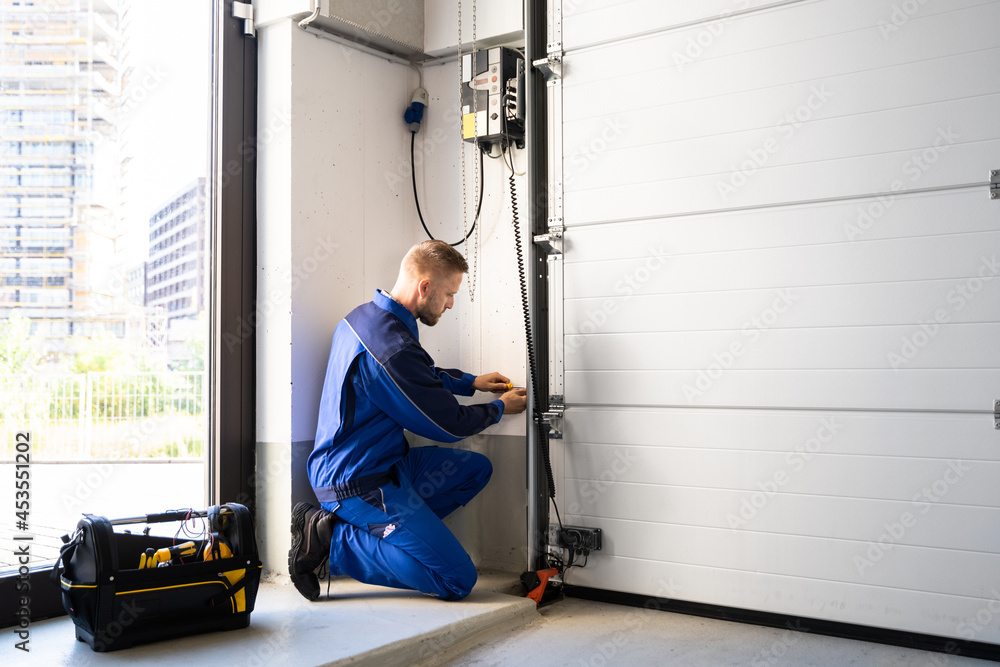 professional in blue uniform working on garage door opener installation
